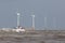 Ship on rough sea horizon by offshore wind farm turbines