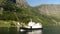 Ship Sailing past Small Village in Norway Fjords