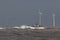 Ship sailing in rough sea around offshore wind farm turbines