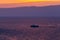 Ship sails on a background of purple sunset sky on the waves of Lake Baikal from Olkhon