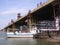 The ship sails through the water on the river under the bridge under construction