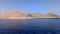 A ship slowly approaching Emporio port with houses barely visible on halki / chalki island on a hilly island of Greece in the