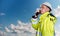 Ship supervisor engineer inspector stands at the dockside in a port. Wearing safety helmet, portable radio and yellow vest. Cargo