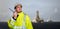 Ship supervisor engineer inspector stands at the dockside in a port. Wearing safety helmet, portable radio and yellow vest. Cargo