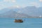 A ship with tourists sails along the Mediterranean Sea against the backdrop of mountains