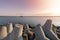 Ship-tugboat goes in high seas to tow cargo ship to port. Beautiful sunset over the pier. Tetrapod breAkwaters in harbor