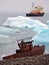 Ship wreck on Arctic coast with icebergs and icebreaker