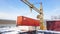 Shipping container and cargo crane at storage yard at winter time aerial view