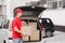 Shipping of parcels by courier to door on car. Deliveryman holds parcels