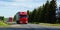 Shipping two red cargo trucks on the road being driven by the sun day