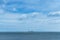 Ships in the sea on the horizon, oil drilling in the sea, calm and cloudy sky