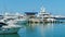 Ships, yachts and boats on blue surface of Black Sea by pier of Commercial seaport of Sochi. Resort city center.