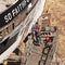 Shipyard worker on platform working on hull of a tugboat. Falmouth, UK