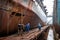 shipyard, with workers welding and painting deck of newly built ship