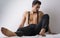 Shirtless athletic young man with suspenders sitting on floor