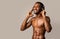 Shirtless Black Sportsman In Headphones Posing Over Beige Studio Background