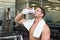Shirtless bodybuilder drinking protein drink sitting on bench