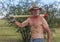 A Shirtless Cowboy Shoulders a Red Pickax