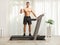 Shirtless fit man posing in a treadmill and gesturing a thumb up sign inside a room