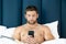 Shirtless hunky man with beard lies naked in bed using mobile phone
