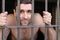 Shirtless man behind metallic bars