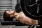 Shirtless man lifting heavy barbell on bench