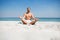 Shirtless man meditating at beach