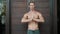 Shirtless man with muscular body does yoga exercises, meditates, shows ok sign