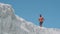 A shirtless muscular male bodybuilder runs along a white mountain