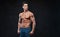 Shirtless muscular male over dark background.