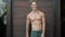 Shirtless muscular man shows sign thumb up, ok, winks, wooden door on background