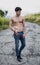 Shirtless muscular young man walking on rural road