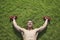 Shirtless, smiling, muscular man lying in grass with dumbbells in Beijing, view from above