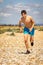 Shirtless teenage boy running on a beach