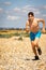 Shirtless teenage boy running on a beach