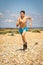 Shirtless teenage boy running on a beach