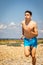 Shirtless teenage boy running on a beach