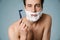 Shirtless white man looking at camera while shaving with foam