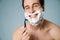 Shirtless white man smiling while shaving with foam