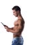 Shirtless young male bodybuiler holding ebook reader or tablet PC