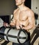 Shirtless young man in gym holding water-filled weight in his hands