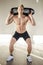 Shirtless young man in gym holding water-filled weight in his hands