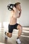 Shirtless young man in gym holding water-filled weight in his hands