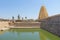 Shiva Virupaksha Temple and green pond, green water. Hampi, Karnataka, India. White yellow restored temple against the blue sky.