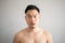 Shock and surprise face of Asian man in topless portrait isolated on gray background