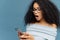 Shocked African American woman gots message from ex, gasps from surprise and excitement, reads stunning news on mobile phone, has