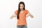 Shocked amazed beautiful caucasian adult daughter in orange outfit, pointing and looking down, saying wow, being