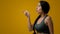 Shocked amazed emotional Indian woman girl female in studio yellow background pointing to side to empty cope space