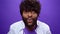 Shocked amazed young bearded black african american man, purple background