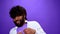 Shocked amazed young bearded black african american man, purple background